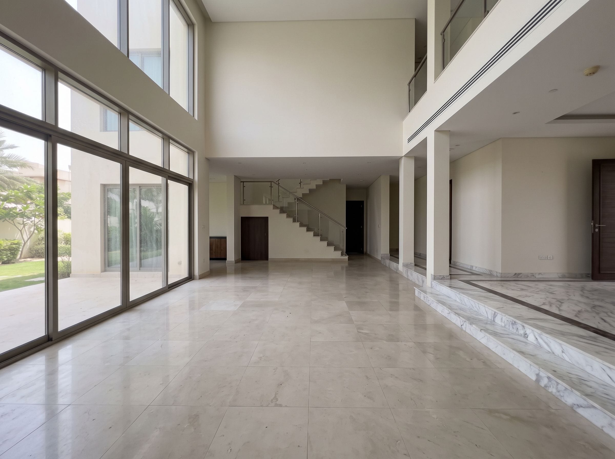 The same double-height villa living room empty, with clean marble floors after the clearance