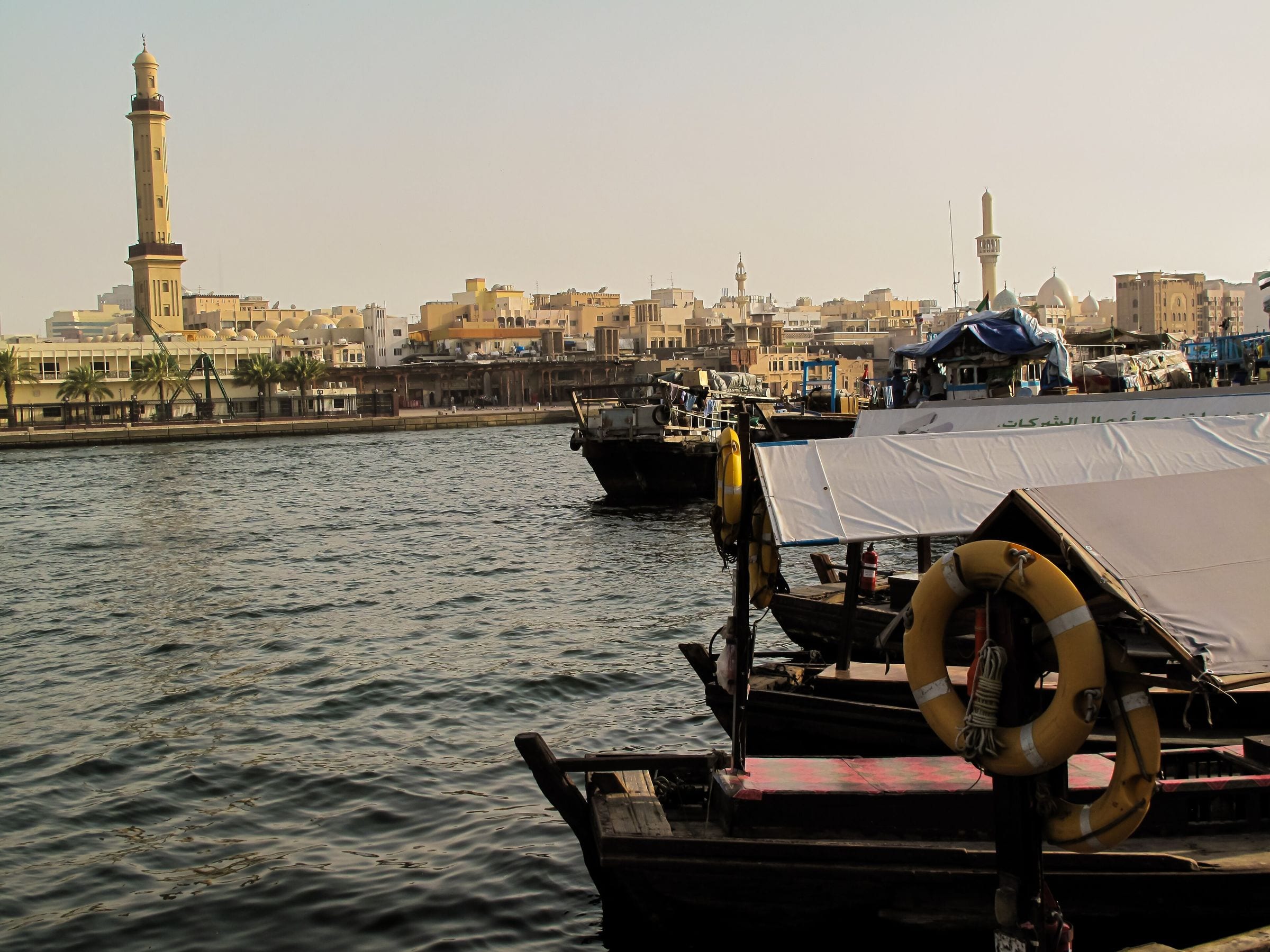 Traditional dhows moored on Dubai Creek in Deira, with the old souk district behind